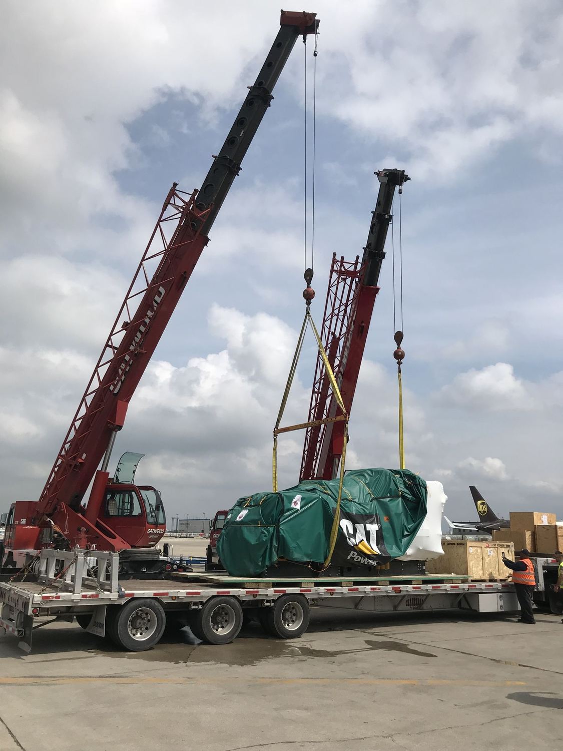 Twin cranes lifting heavy project cargo onto a lowboy trailer