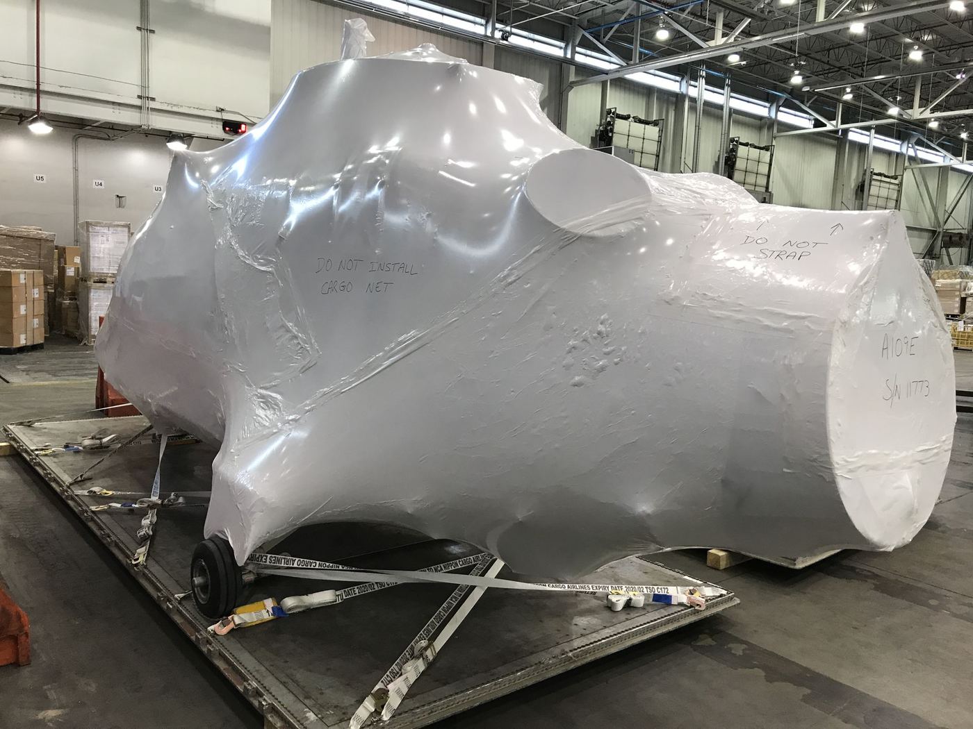 Shrink-wrapped oversize cargo staged on a pallet in a cargo warehouse